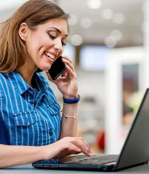 Business professional using a phone and laptop while working remotely